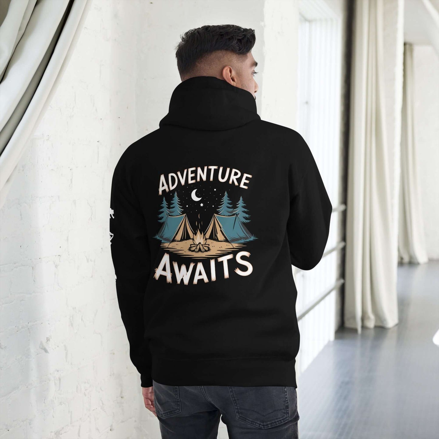 Back view of a man in a black hoodie with 'Adventure Awaits' and camping design, perfect for outdoor enthusiasts.