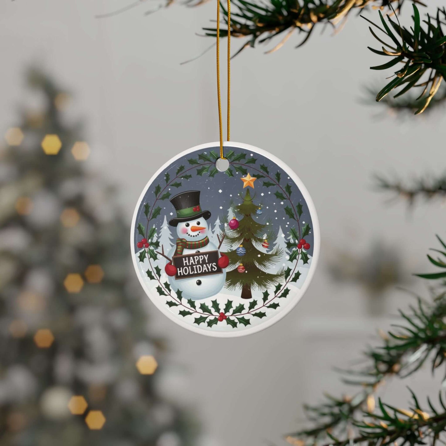 Festive ceramic ornament with snowman and Christmas tree design, "Happy Holidays" text, hanging on Christmas tree branch.