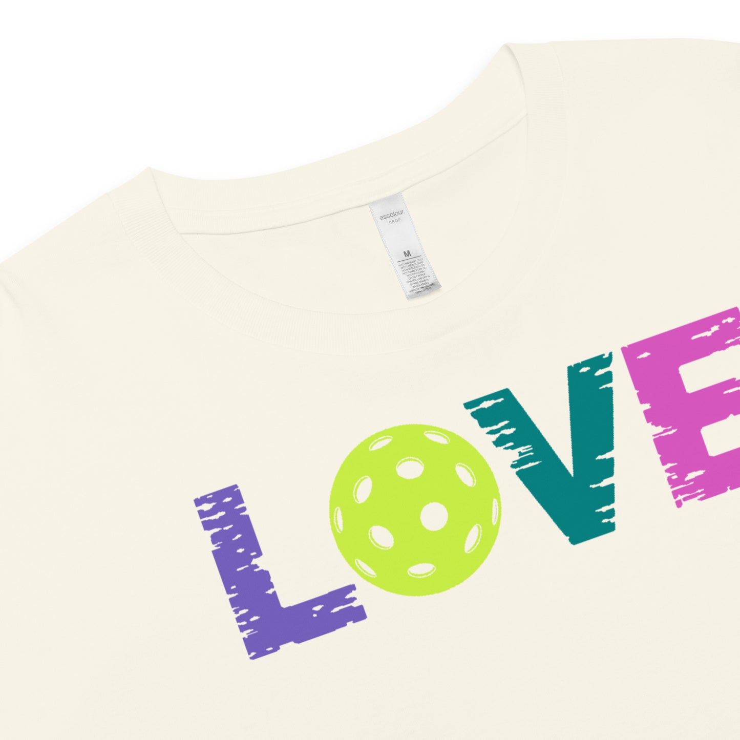 Women's LOVE Pickleball Crop Top featuring colorful text and a pickleball graphic on a soft cream background.