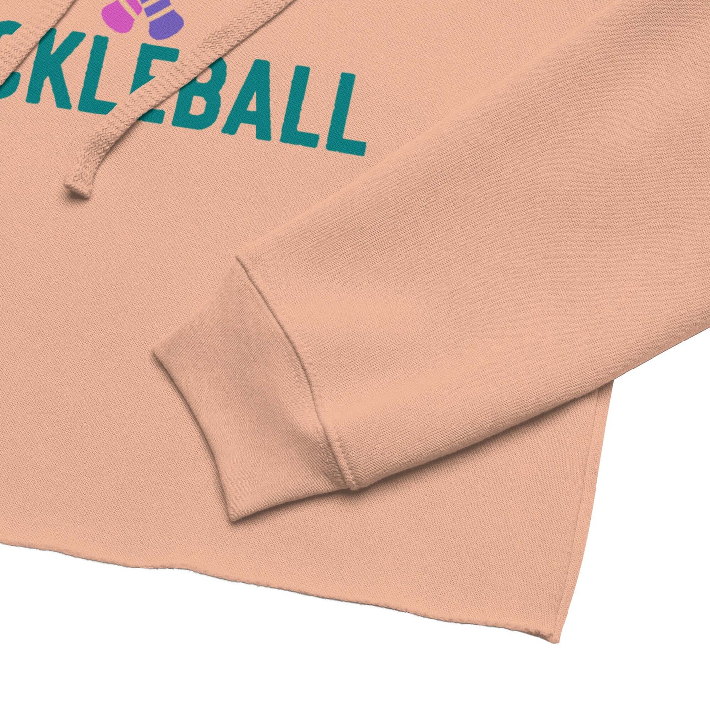 Close-up of Women's Peace, Love, Pickleball Crop Hoodie showcasing sleeve and raw hem detail in peach color.