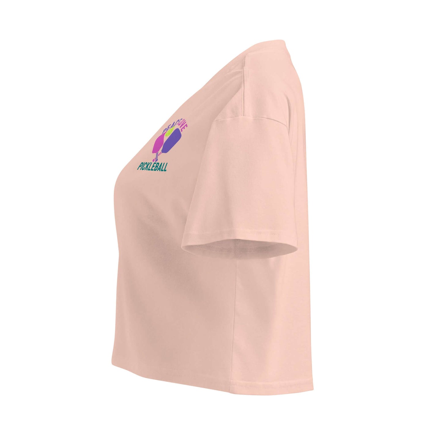 Side view of Women's Peace, Love, Pickleball Crop Top in soft peach color, featuring sporty graphics.