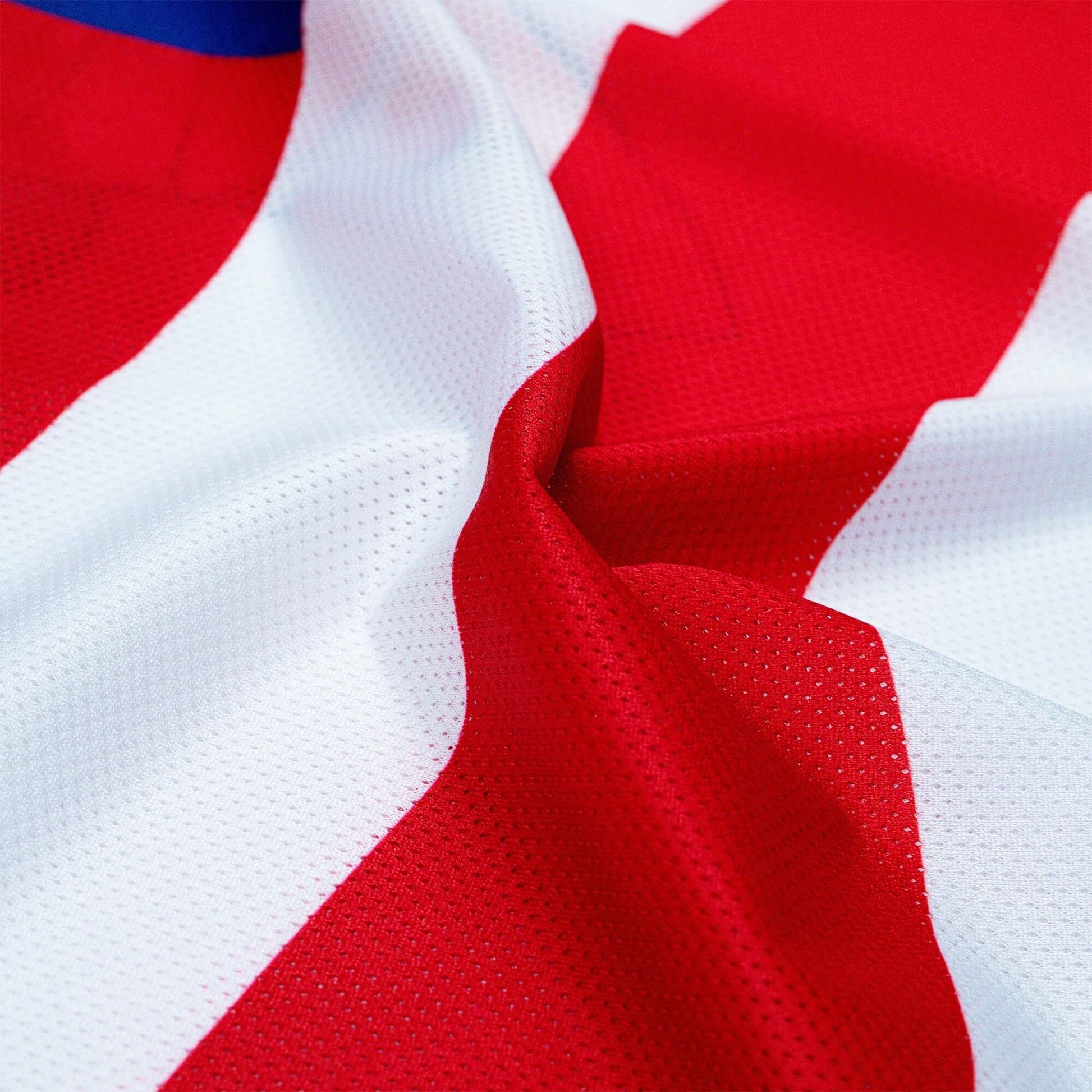 Red and white vented polyester mesh fabric of Crossbones Merica Jersey, showcasing breathable sportswear material.