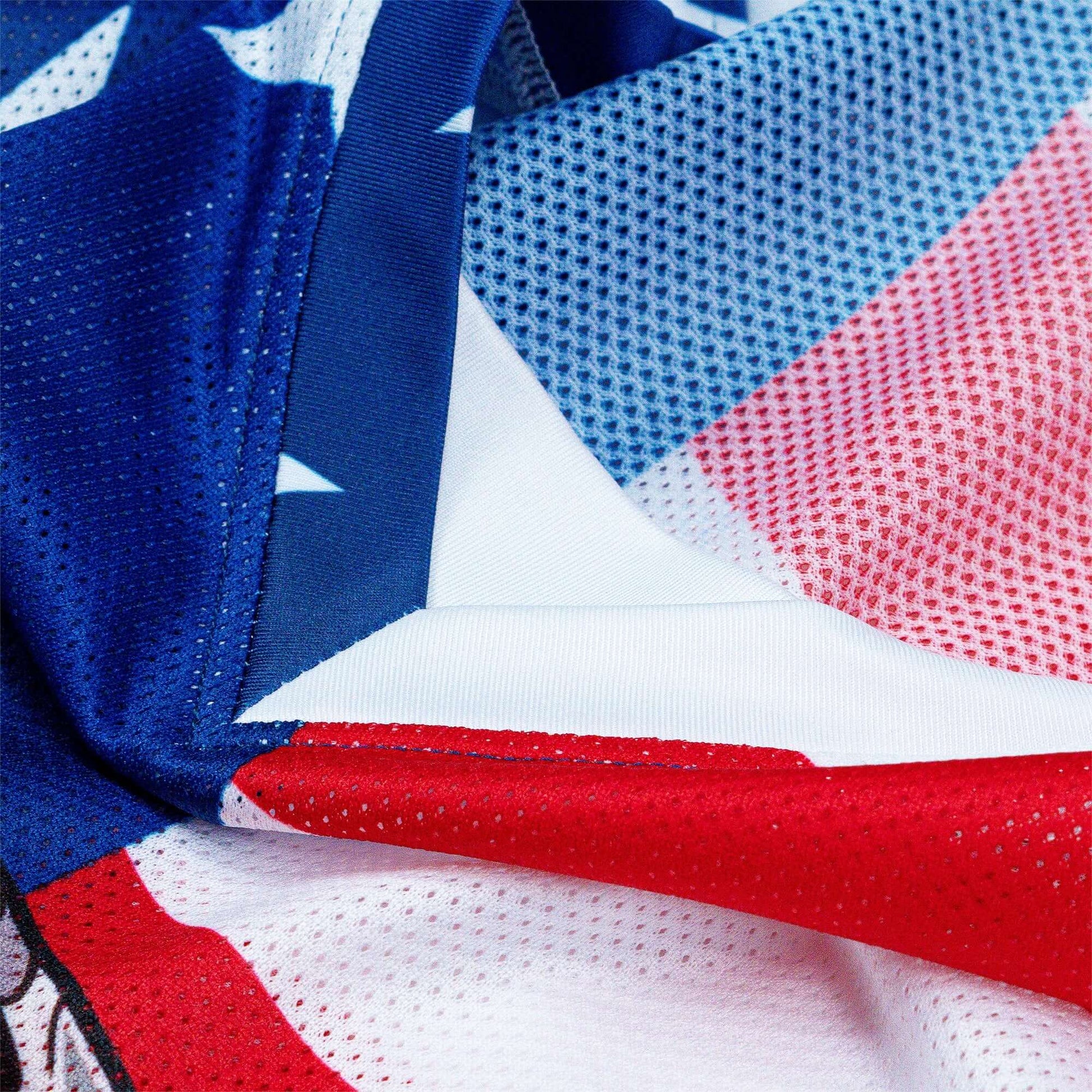 Close-up of the Crossbones Merica Jersey fabric featuring blue, red, and white mesh design with star patterns, highlighting its texture.