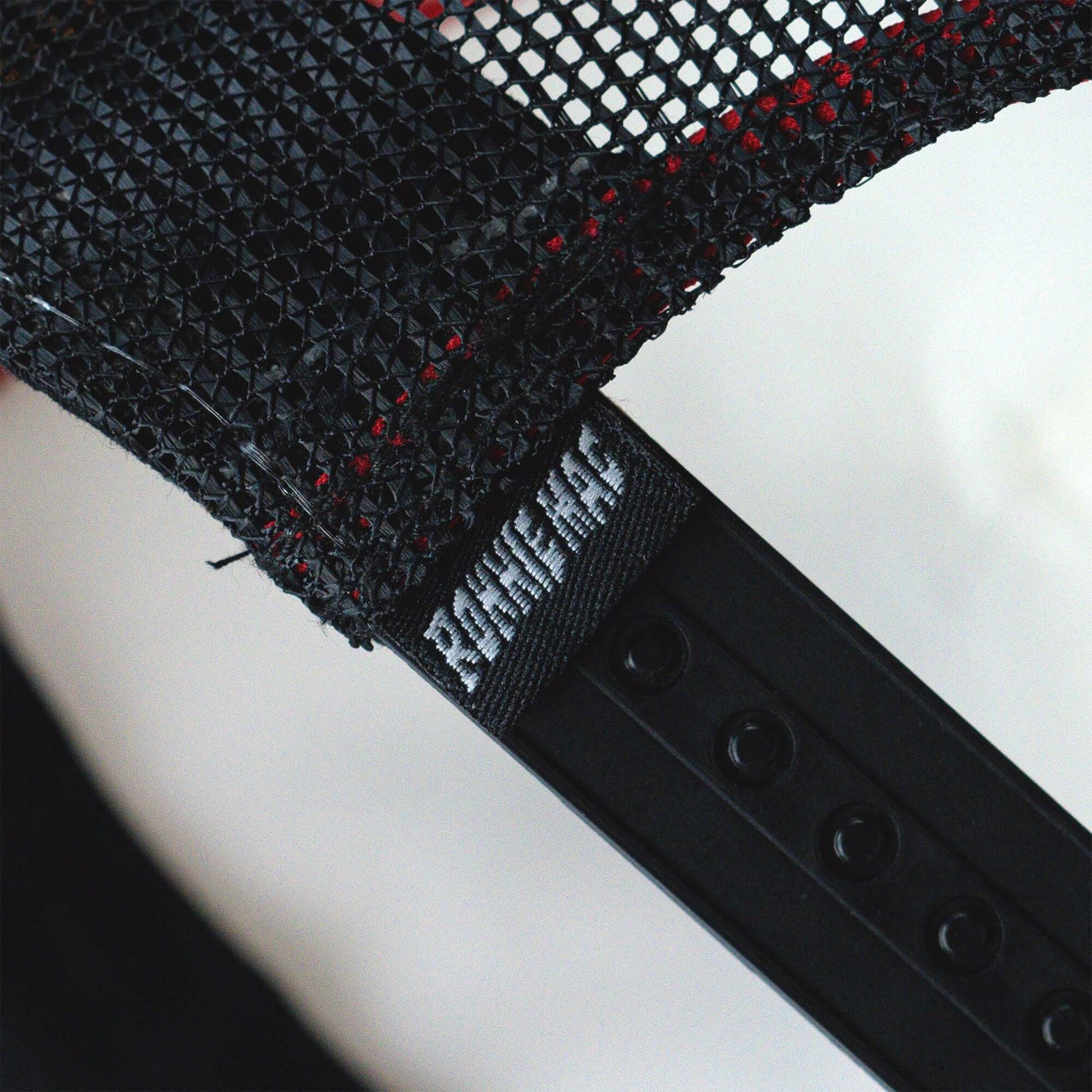 Close-up of black mesh and snapback clasp on a Crossbones signature trucker hat.
