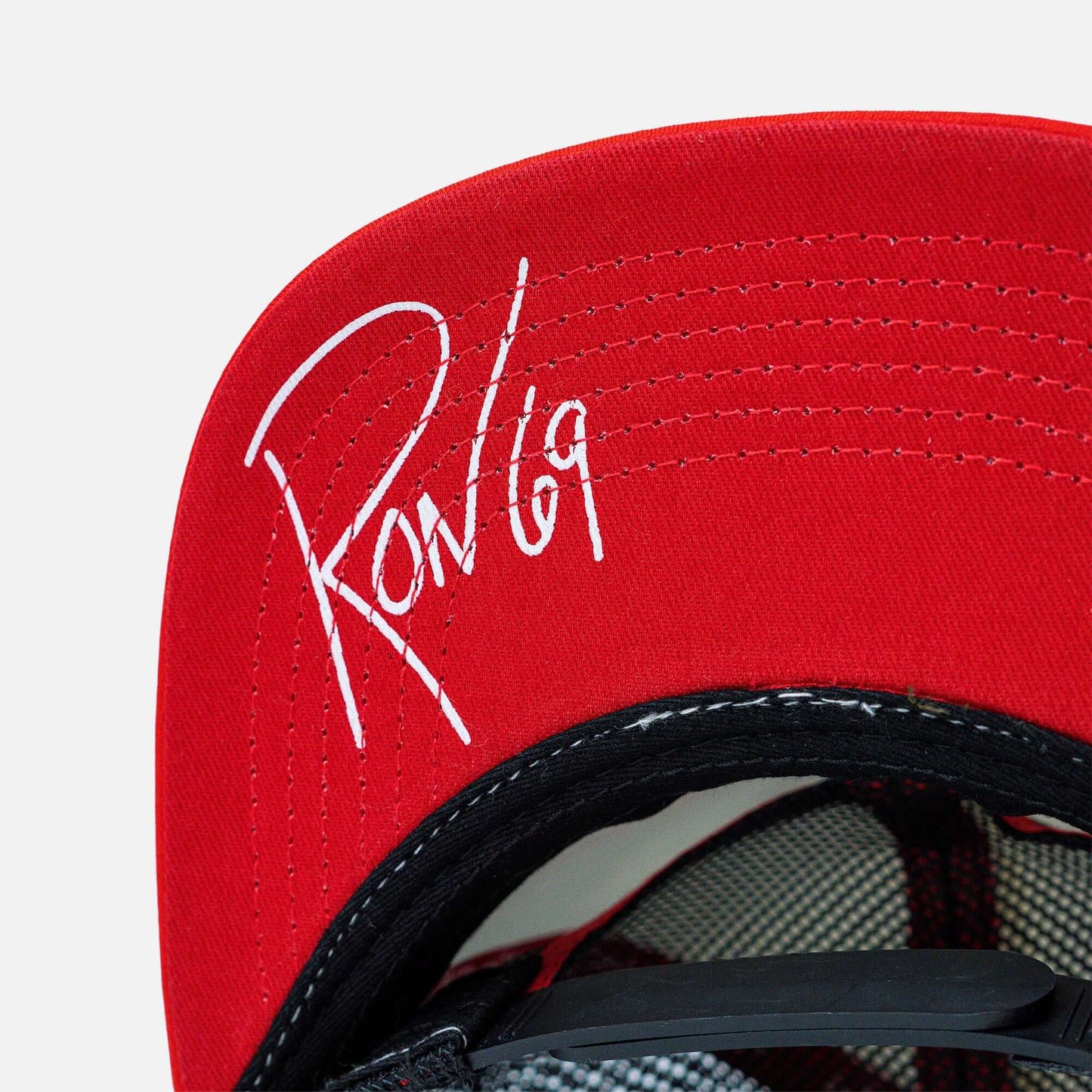 Red trucker hat with signature embroidery under the brim, showcasing a classic style perfect for casual wear or outdoor activities.