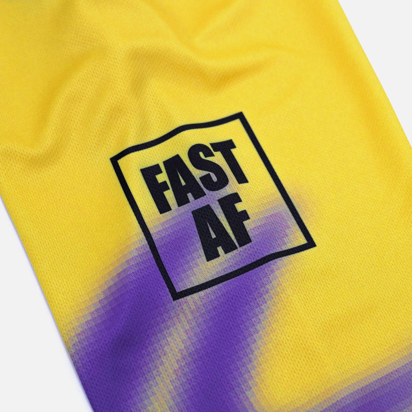 Yellow and purple Fast AF jersey fabric close-up showing text design.