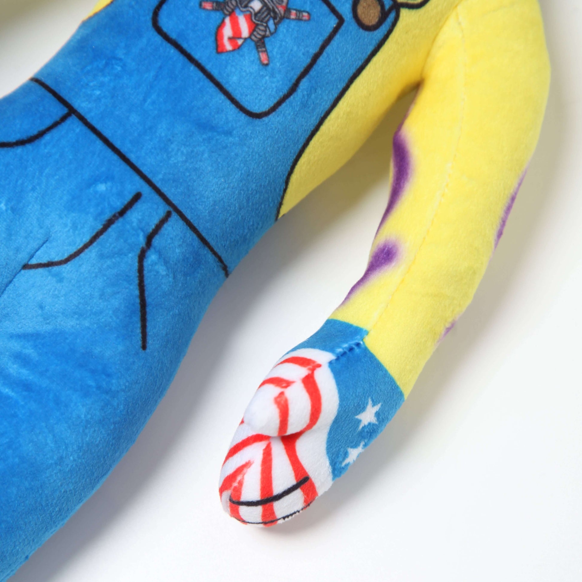 Close-up of Lil Ronnie Plush toy in colorful overalls, showcasing detailed patterns and vibrant colors, highlighting playful mischief.