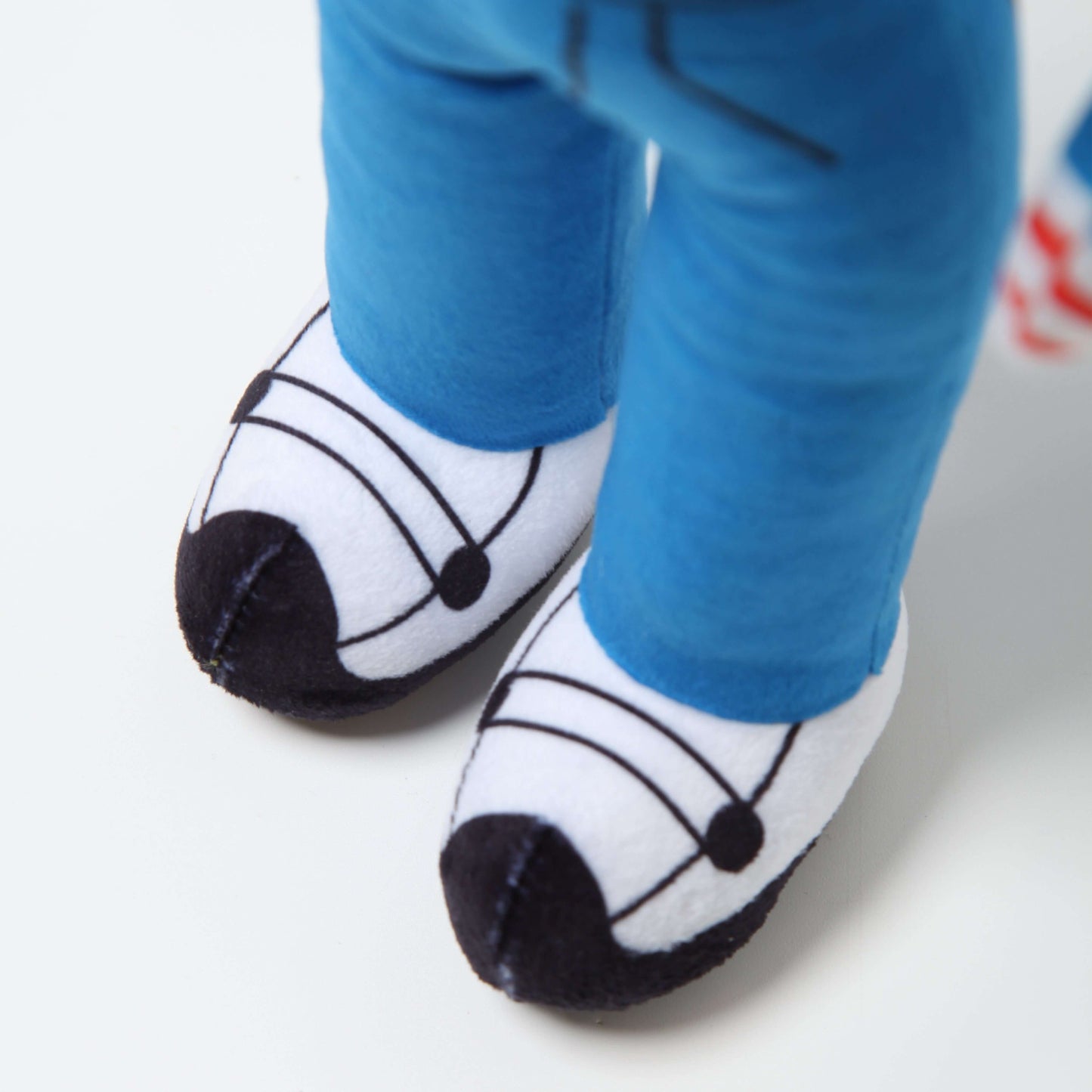 Close-up of Lil Ronnie Plush, featuring detailed blue pants and white shoes with black accents.