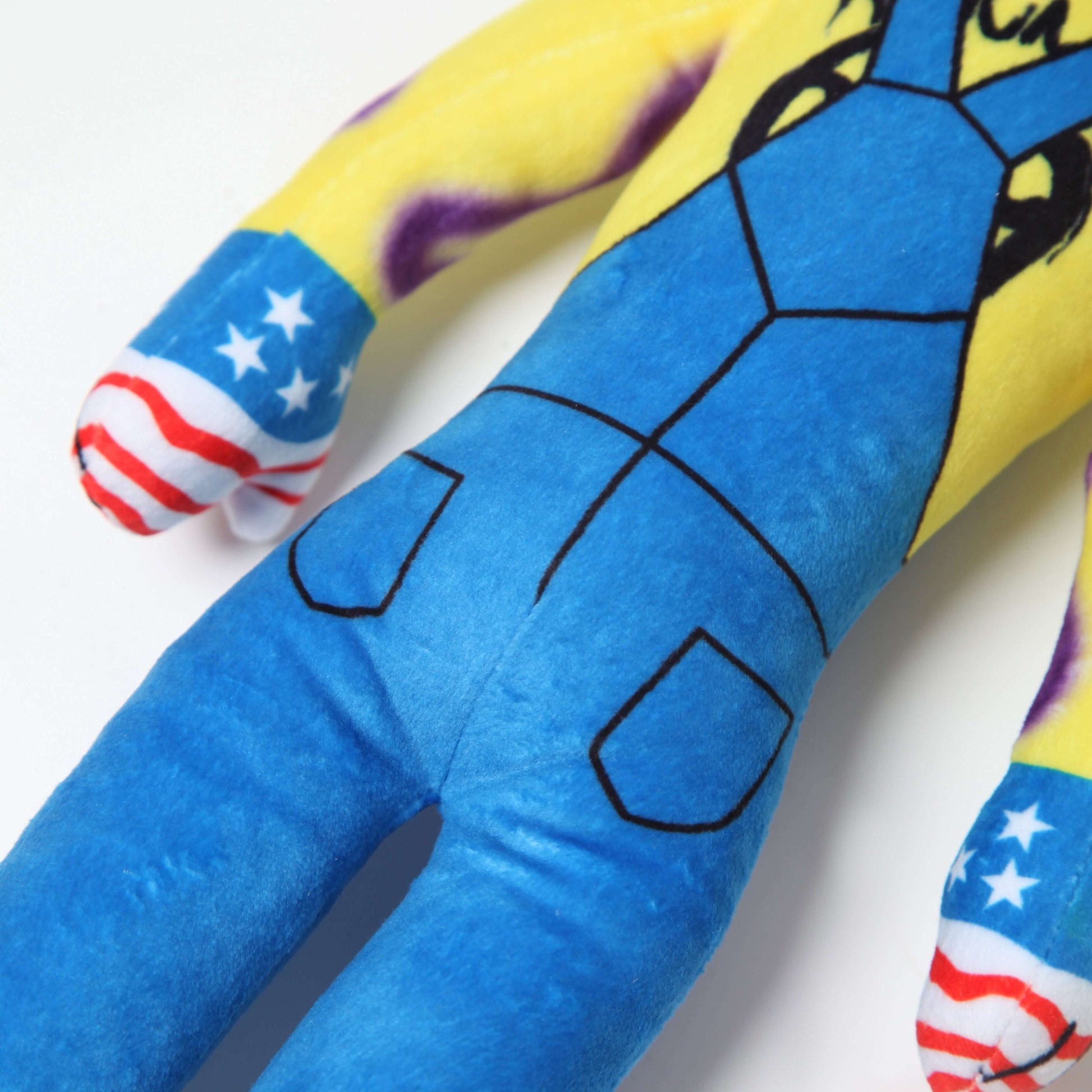 Lil Ronnie Plush toy in blue overalls and American flag gloves, showcasing its playful and mischievous character.