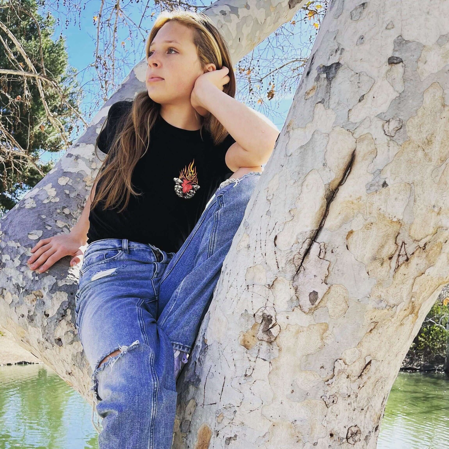 Person wearing No Mercy Mixed Doubles Flaming Heart Pickleball T-Shirt while sitting on a tree.