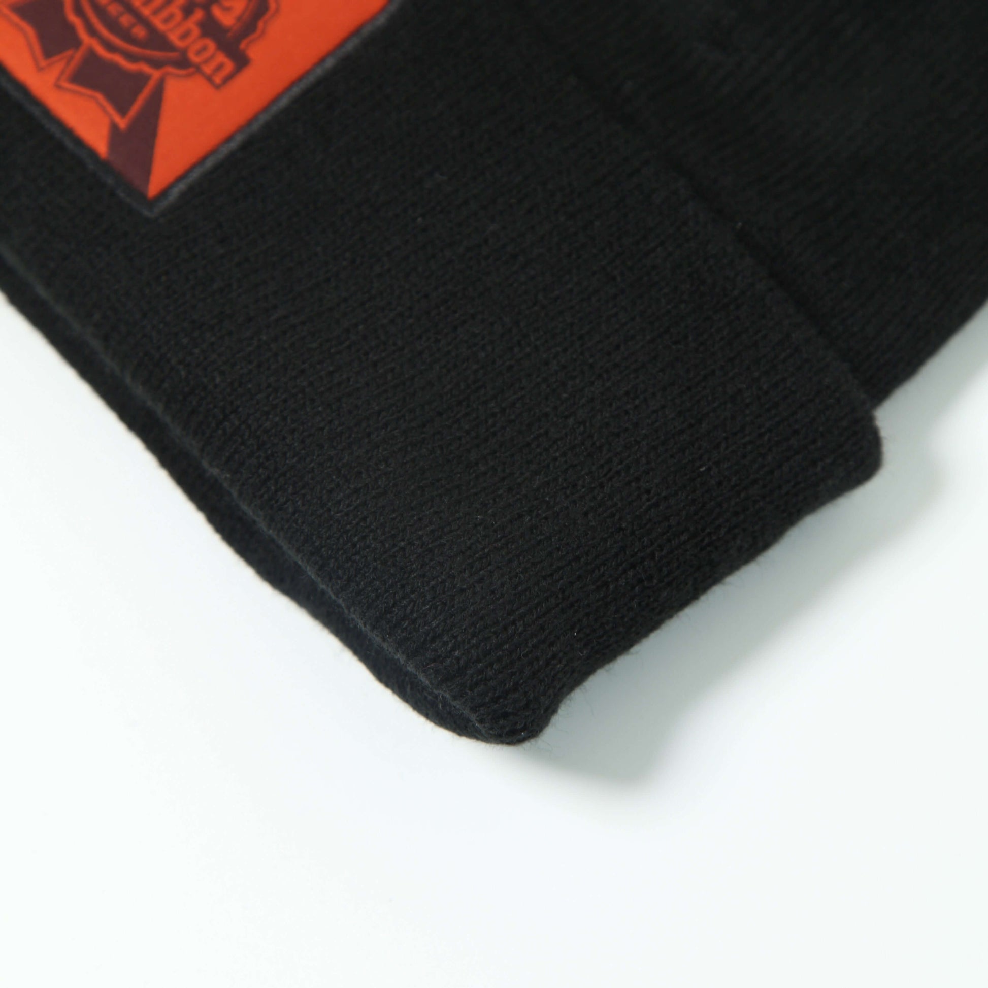 Black beanie featuring Ron's Blue Ribbon Beer logo, showcasing durable material for motocross enthusiasts.