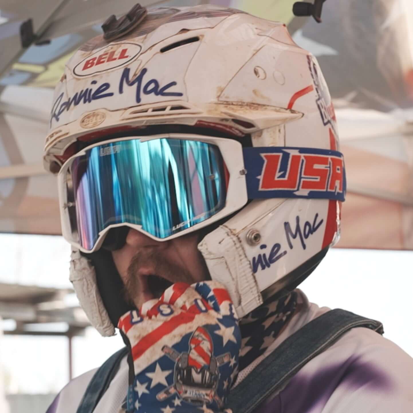 Rider wearing USA Merica Goggles with Oakley lens and patriotic gloves under a helmet at motocross event.