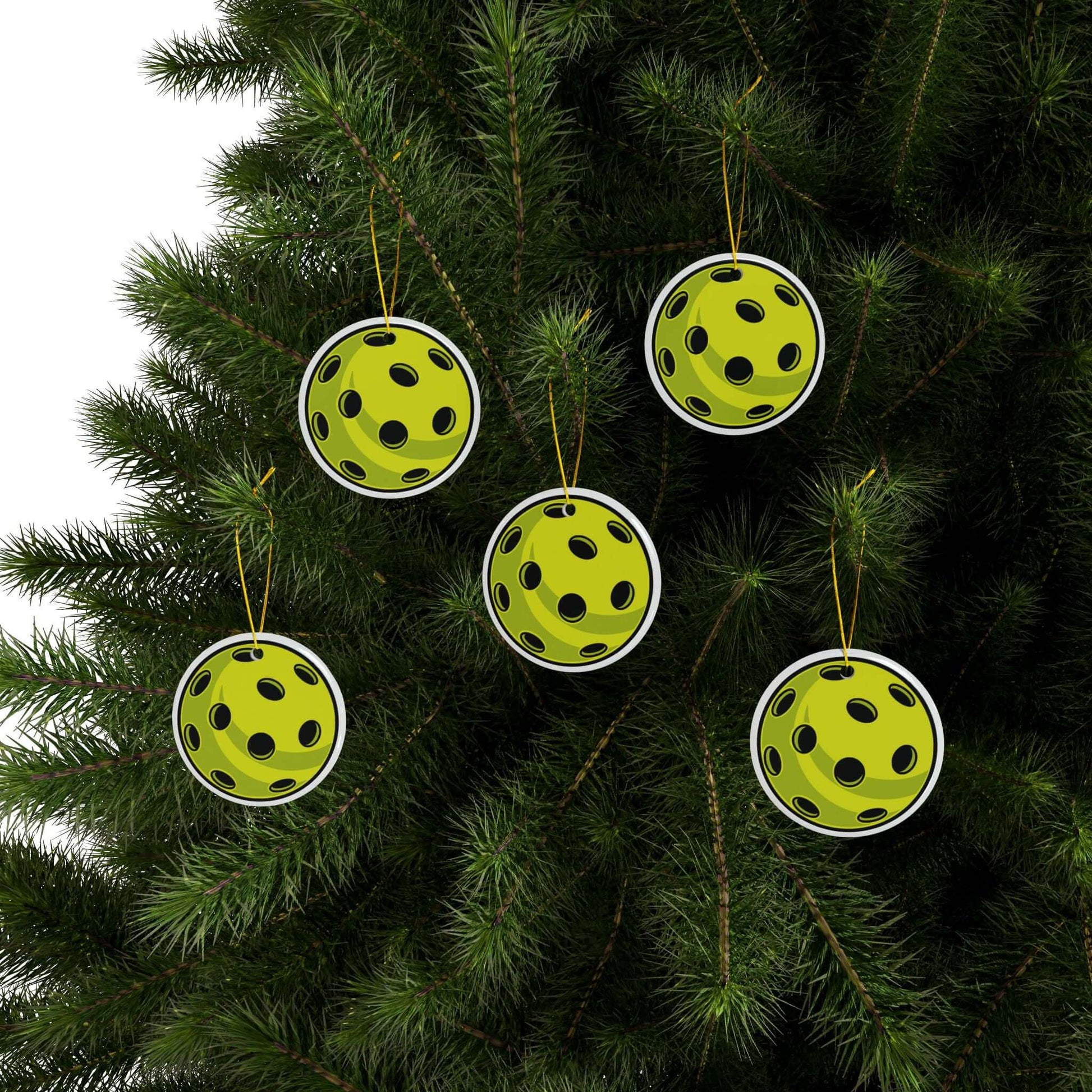 Pickleball Christmas ornaments with vibrant print hanging on a tree, perfect holiday decor for pickleball enthusiasts.