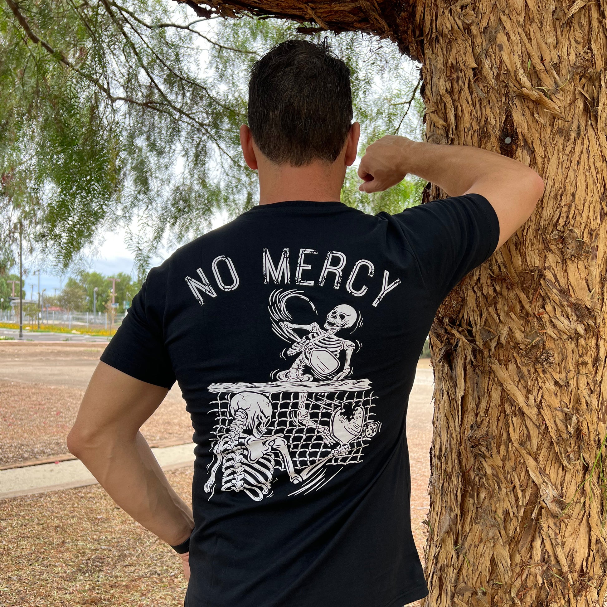 No Mercy Pickleball T-Shirt - Back Angle - Leaning on a Tree